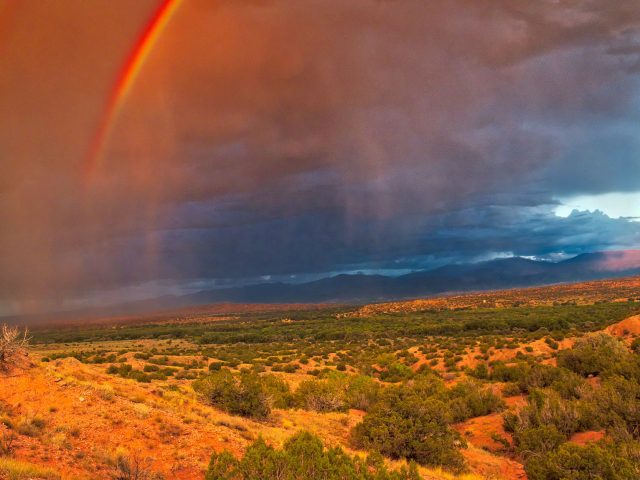 A double red rainbow shines brightly at sunset over Northern New Mexico