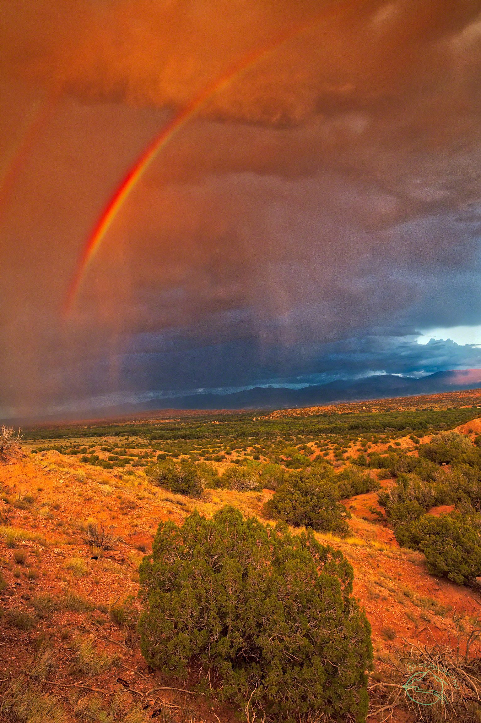 A double red rainbow shines brightly at sunset over Northern New Mexico