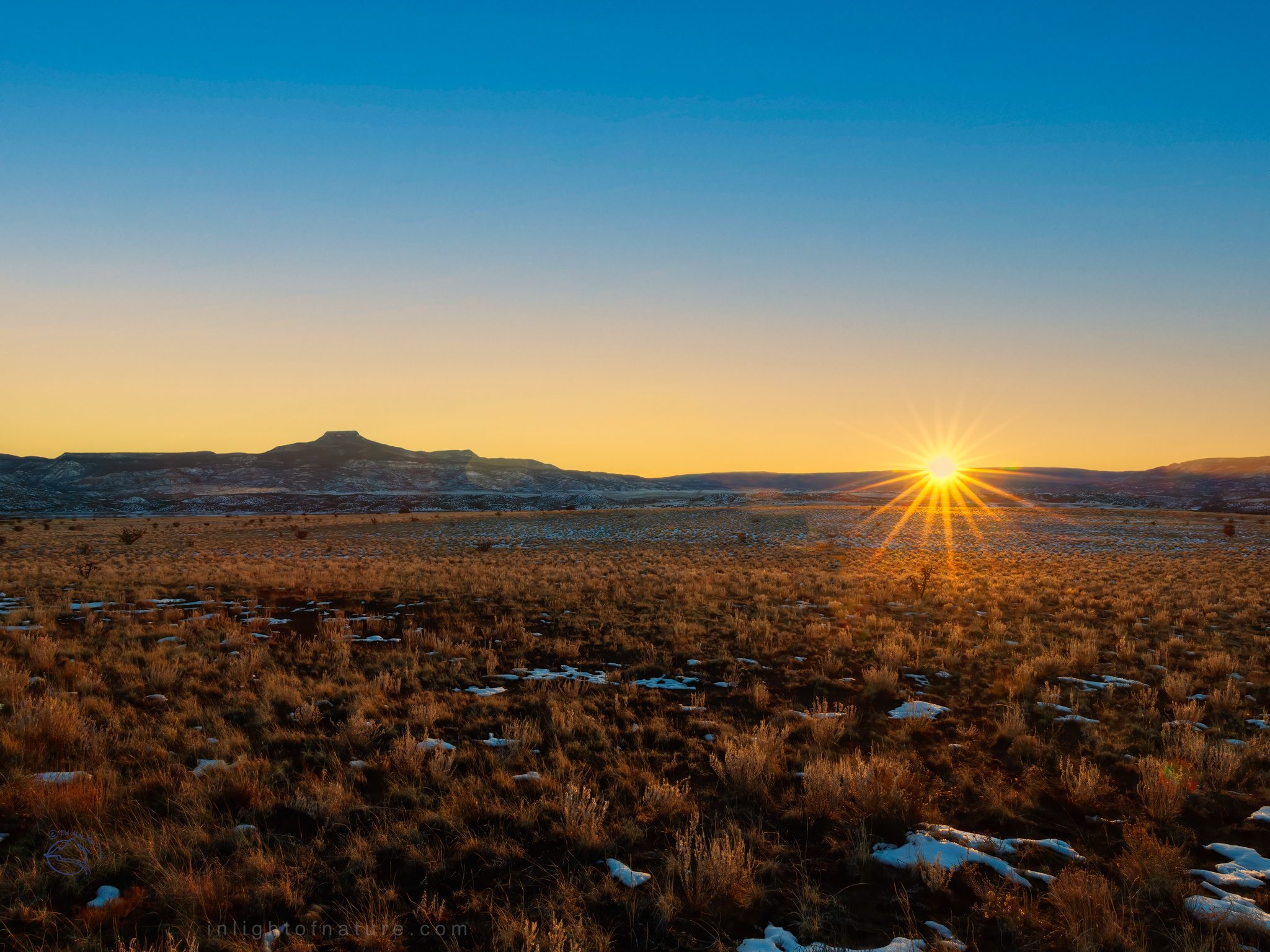 The setting sun on the horizon at Winter Solstice by Cerro Pedernal